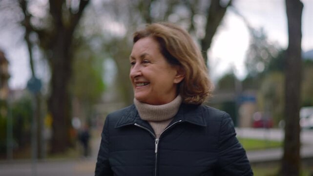 Joyful Caucasian senior woman laughing while walking in the park