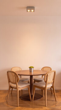 Modern Minimalist Dining Room Interior with Round Wooden Table and Four Stylish Cane Chairs in Warm Lighting