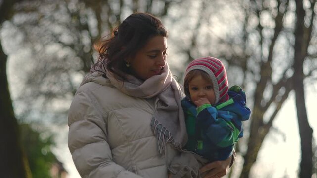 Caucasian mom holding her toddler outdoors and looking around together