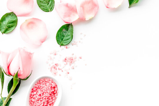 Pattern with rose oil cosmetics. Rose petals, spa salt on white background top view copyspace