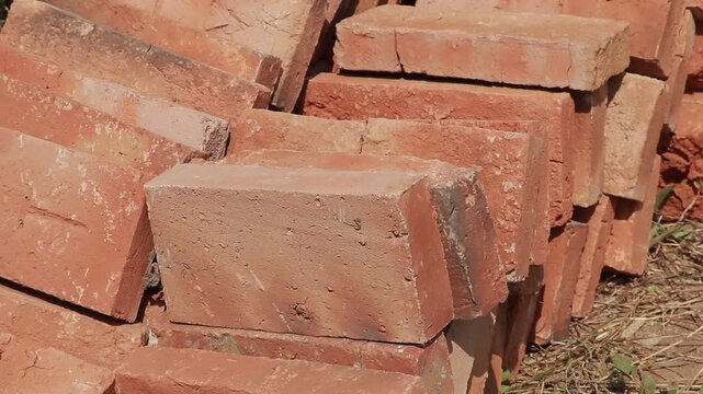 Close up view of a pile of red clay bricks stacked for construction and masonry work on an outdoor building site
