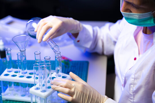 Close Up Of Vaccine Sample Poured Into Test Tube Rack Through Funnel In Research Lab