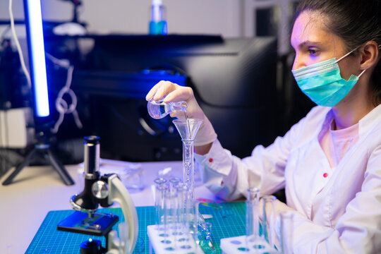 Scientist pours flask sample through funnel during alternative protein source research in laboratory