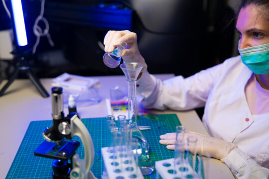 Scientist filters flask sample through funnel during alternative protein research in modern laboratory