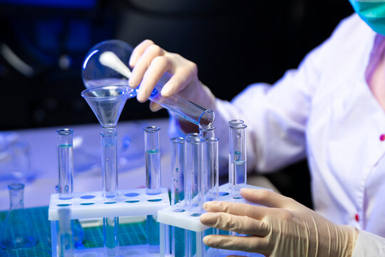Close Up Of Researcher Pouring Vaccine Liquid From Flask Into Test Tubes For Clinical Trial
