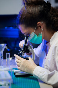 Close Up Of Female Researcher Looking Through Microscope During Vaccine Development Study
