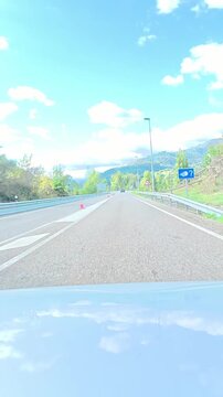 Vehicle driving along scenic highway roads and through a mountain tunnel in aller valley under blue cloudy sky