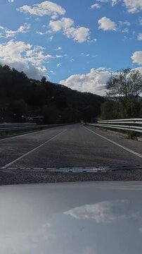 Vehicle traveling along a scenic mountain highway through the aller valley in asturias, showcasing green hills and cloudy skies