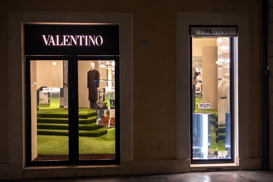Valentino boutique storefront with illuminated sign and window displays at night in the center of Rome, Italy