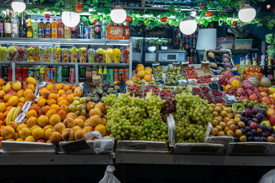 Fruit stall at night with grapes, peaches, oranges and soft drinks on display in a market in Rome, Italy