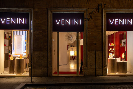 Illuminated Venini glassware boutique storefronts with display windows at night on a street in Rome, Italy