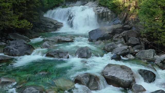 Aerial flight over whitewater cascades and boulders on a mountain river in British Columbia