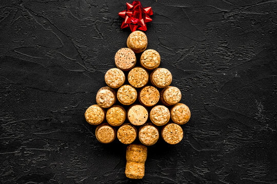 Corks of wine bottles in shape of new year spruce on black background top view copyspace