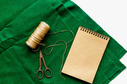 Tailor's work desk. Textile, notebook and tools on white background top view