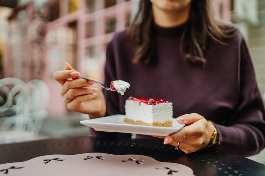 Woman enjoying berry cheesecake at an outdoor cafe