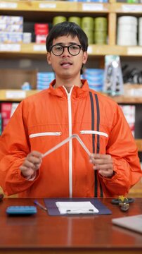 Warehouse clerk holding a white metal shelf bracket while explaining product details to camera