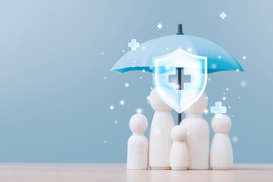 Wooden family figures under a blue umbrella with a medical cross and protective shield. Concept family insurance, healthcare coverage, financial security, health protection and peace of mind.