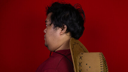 A sharp side profile portrait of a young Asian male facing left with a calm, neutral facial expression. The confident subject wears a maroon top, featuring a detailed brown cowboy © M. Faisal Riza
