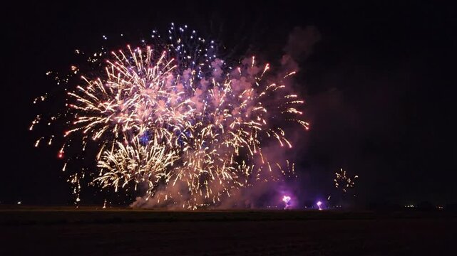 Fireworks display exploding in colorful bursts over a night field