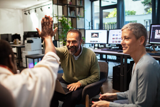 Coworkers celebrate with a high five in the office