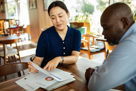 Woman presenting charts to colleague at cafe table