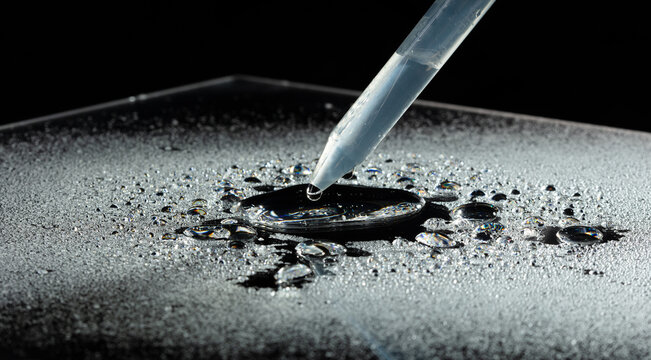 Experimental Science drop add water on a dark surface tension by dropper. Water drops rolling off waterproof coating surface tension physics detail clean background, Macro Photography