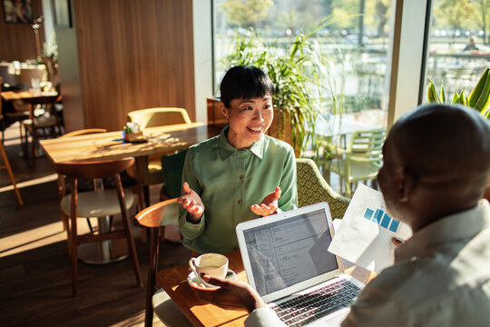 Smiling woman discussing data with colleague in cafe