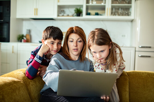 Mother and children watching laptop together at home