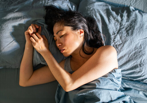 Woman sleeping on side in bed at home