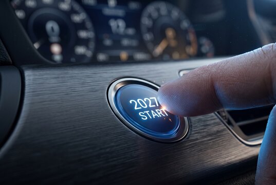 Finger pressing glowing 2027 start button on car dashboard, showcasing concept of new year launch, fresh start, business goals, motivation and beginning of a new journey