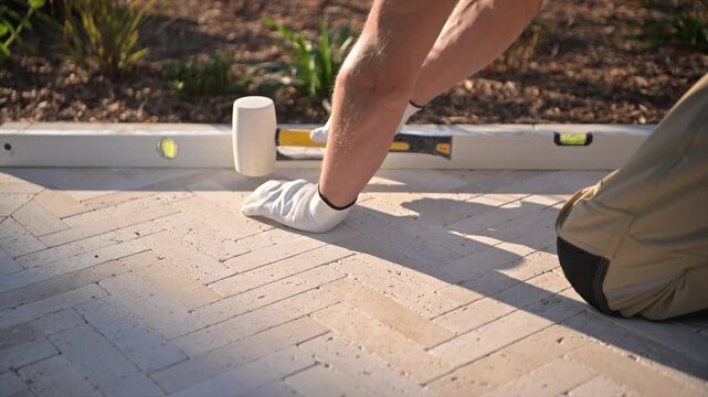 Worker aligning patio paving with a mallet and layout square