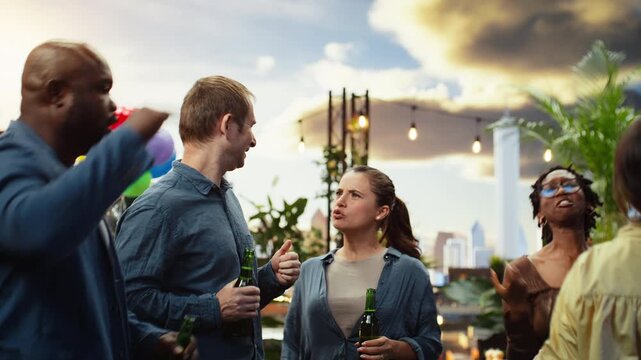 Friends dance and gesture beside a barbecue grill at a rooftop party with balloons and string lights, sharing playful conversation and outdoor celebration.