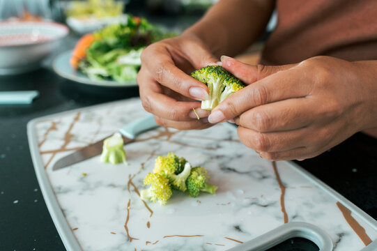 Woman's hands preparing fresh broccoli for healthy salad