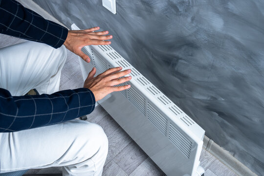 A person is warming their hands by a heater.