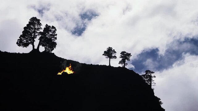 Glowing Bonfire On Hillside Silhouette With Clouds Drifting In Background - 4K