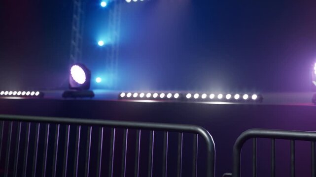 Bright lights shine upon a stage ready for an exciting performance. The energy in the air builds as barriers define the space, creating anticipation for the crowd.