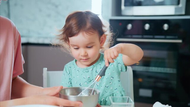 Child mixes ingredients with joyful focus. Parent guides her gently in the kitchen. Warm light highlights their shared activity. Perfect for parenting, education, or family lifestyle content