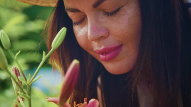 Woman smiles softly, inhaling fresh lily scent. Straw hat rests gently on her brow. Soft light enhances her calm, contented expression. Ideal for garden, wellness, or nature-inspired content