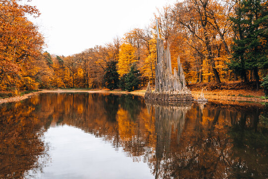 View of the Rakotzbrucke, also known as the Devil's Bridge, reflected in the calm water of the Rakotzsee, surrounded by vibrant autumn foliage in the Kromlau Park in Gablenz, Sachsen, Germany.