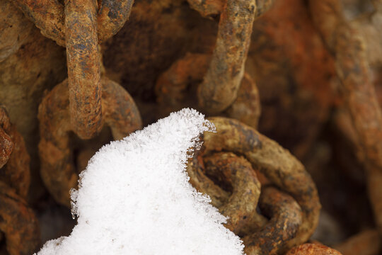 View of rusty metal chains covered with fresh snow and ice crystals in the Arctic landscape in Abisko, Norrbotten County, Sweden.