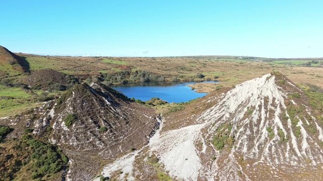 Aerial view flying over slag heaps and a lake at an abandoned clay pit