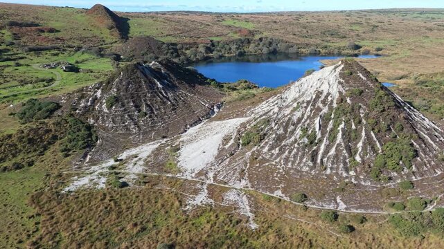 Aerial drone sideways roll over industrial slag heaps and flooded quarry lake
