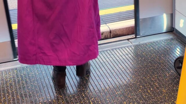 Close-up of a London subway passenger stepping up from a subway train onto the station platform, navigating the height difference and gap while exiting. 15557  