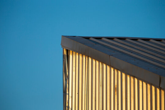 Minimalist view of corrugated metal warehouse roof against blue sky.
A high-quality minimalist photograph capturing the clean geometric lines of a corrugated steel or corrugated metal sheet roof