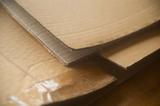 Close up of stacked brown corrugated cardboard sheets with selective focus.
A high-quality close-up photograph capturing the textured layers of stacked brown corrugated cardboard boxes 