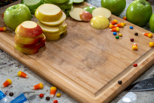 Colorful Apple Slices and Candy Corn on Wooden Cutting Board with Green Apples Display Variety scene