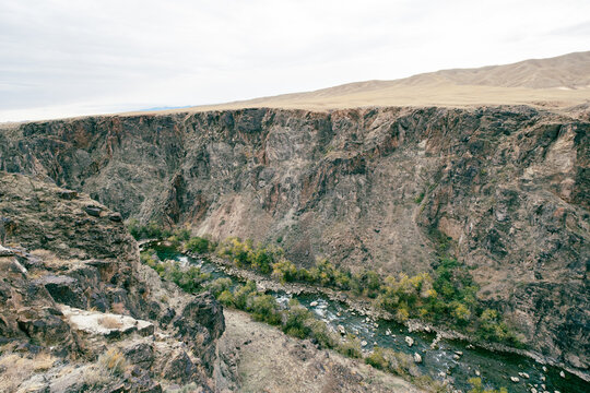 View of the Black Canyon with a river flowing through the deep rocky gorge, surrounded by steep cliffs and sparse vegetation in Aktogay, Almaty Region, Kazakhstan.