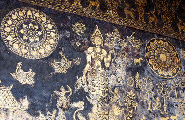 Golden Buddhist murals and intricate circular mandala designs adorn the dark walls of Wat Xiengthong temple in Luang Prabang, Laos. © Eugene Ga