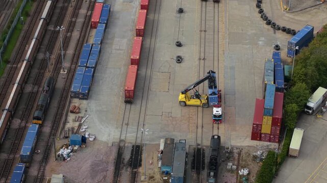 Aerial view of Daventry International Rail Freight Terminal with reach stacker moving shipping containers at Kilsby, England, United Kingdom.