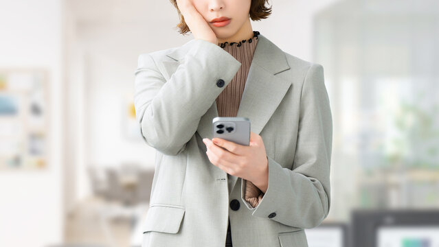 スマートフォンを見て考える女性・ビジネスウーマン